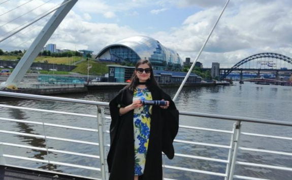 Deema posing on the Millennium Bridge in her graduation gown